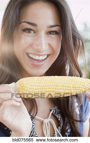 Stock Photography - Hispanic woman eating ear of corn. Fotosearch
