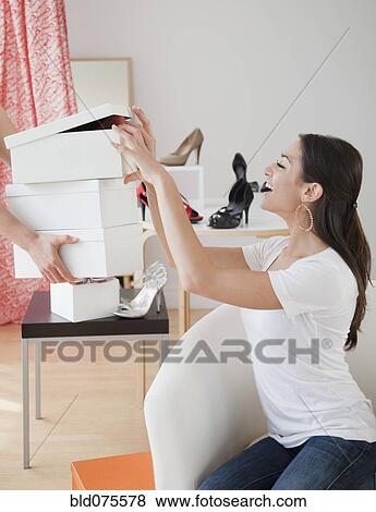 Stock Photo - Hispanic woman eyeing shoe boxes at store. Fotosearch