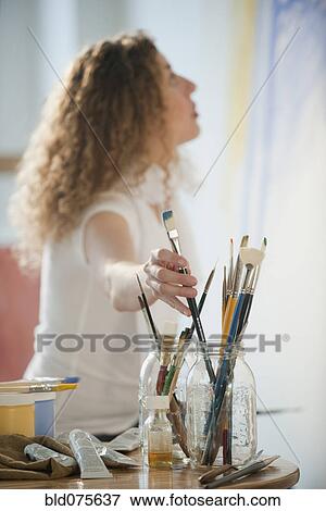 Hispanic woman reaching for paintbrush View Large Photo Image Stock Photo - Hispanic woman reaching for paintbrush. Fotosearch