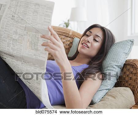 Picture - Hispanic woman reading newspaper. Fotosearch