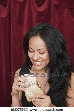Stock Image - Hispanic woman removing money from wallet. Fotosearch