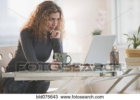 Hispanic woman using laptop in home office View Large Photo Image Stock Image - Hispanic woman using laptop in home office. Fotosearch