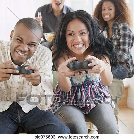 Stock Image - Man and woman playing video game and making faces. Fotosearch
