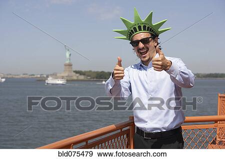 Stock Photo - Mixed race businessman on ferry wearing Statue of Liberty hat. Fotosearch