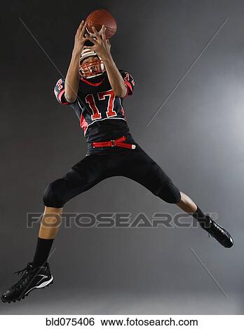 Stock Photograph - Mixed race football player catching football. Fotosearch