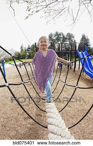 Stock Image - Mixed race girl on playground equipment. Fotosearch