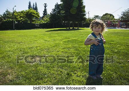 Mixed race girl wearing overalls in park View Large Photo Image Stock Photography - Mixed race girl wearing overalls in park. Fotosearch
