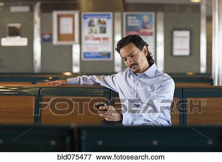 Stock Photo - Mixed race man looking down at cell phone. Fotosearch
