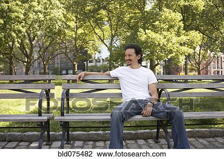 Mixed race man relaxing on park bench View Large Photo Image Stock Image - Mixed race man relaxing on park bench. Fotosearch