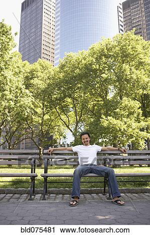 Mixed race man smiling on park bench View Large Photo Image Stock Image - Mixed race man smiling on park bench. Fotosearch