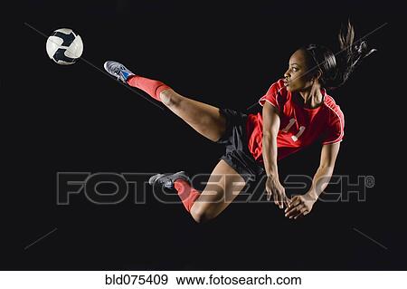 Mixed race soccer player kicking soccer ball in mid-air View Large Photo Image Stock Photo - Mixed race soccer player kicking soccer ball in mid-air. Fotosearch