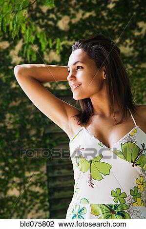 Stock Image - Mixed race woman smiling with hand behind head. Fotosearch