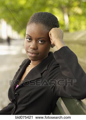 Stock Image - Serious African businesswoman sitting on bench. Fotosearch