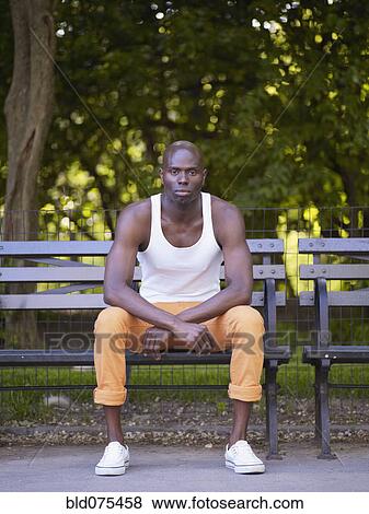 Serious African man sitting on bench View Large Photo Image Stock Photo - Serious African man sitting on bench. Fotosearch