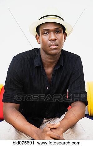 Stock Image - Serious African man sitting with hands clasped. Fotosearch