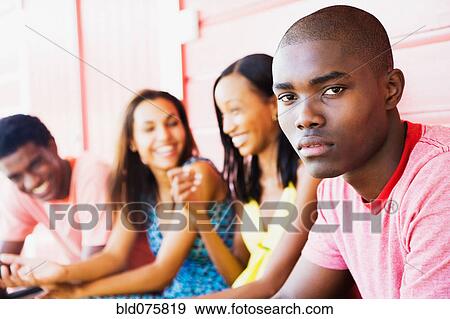 Stock Photo - Serious African man with friends in background. Fotosearch