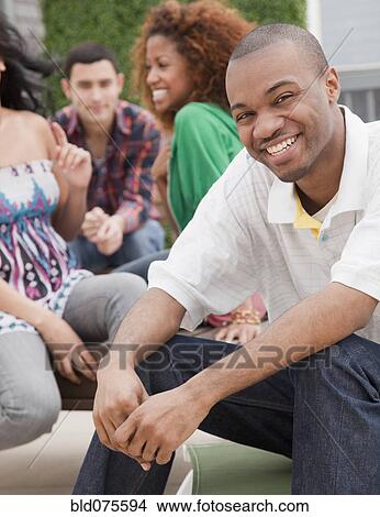 Picture - Smiling African man with friends in background. Fotosearch