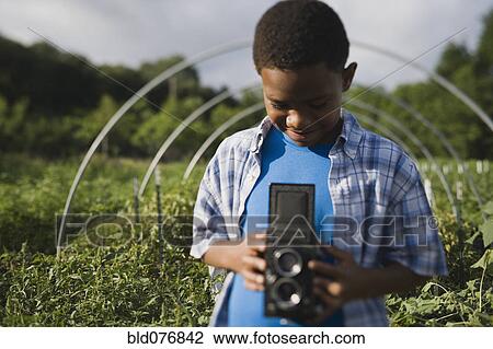 African boy holding retro camera in garden View Large Photo Image Stock Image - African boy holding retro camera in garden. Fotosearch
