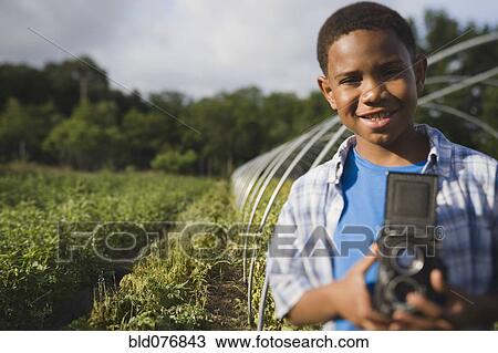 African boy holding retro camera in garden View Large Photo Image Stock Image - African boy holding retro camera in garden. Fotosearch