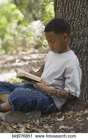 African boy reading book against tree View Large Photo Image Stock Image - African boy reading book against tree. Fotosearch