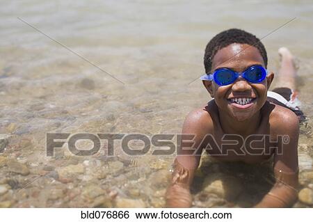 African boy wearing goggles and laying in shallow lake View Large Photo Image Stock Photograph - African boy wearing goggles and laying in shallow lake. Fotosearch