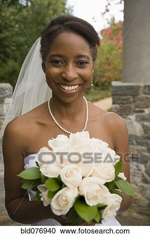 African bride holding rose bouquet and smiling View Large Photo Image Stock Image - African bride holding rose bouquet and smiling. Fotosearch