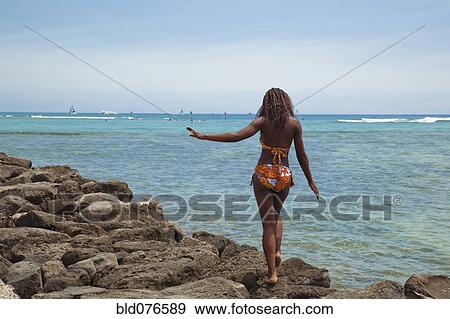 African woman in bikini walking on rocks on beach View Large Photo Image Stock Photo - African woman in bikini walking on rocks on beach. Fotosearch