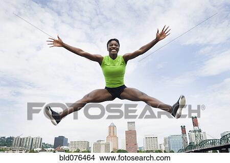 African woman jumping with city in background View Large Photo Image Picture - African woman jumping with city in background. Fotosearch