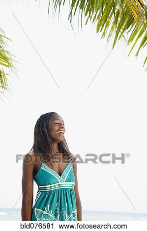 Stock Image - African woman laughing on beach. Fotosearch
