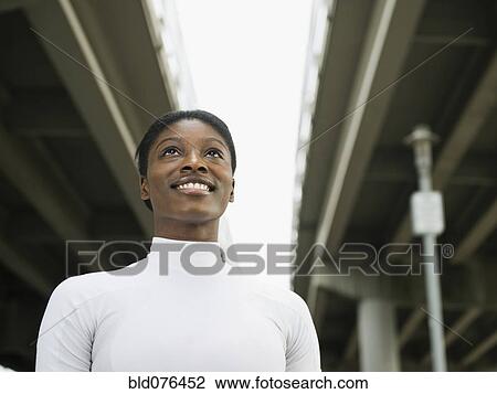 Stock Image - African woman smiling under freeway overpass. Fotosearch