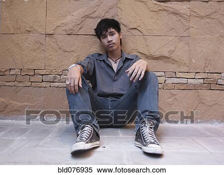 Asian man sitting against wall View Large Photo Image Stock Photography - Asian man sitting against wall. Fotosearch