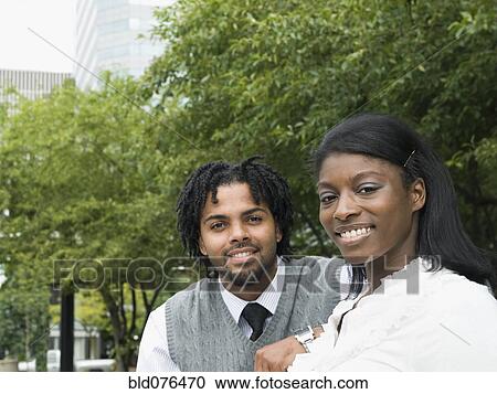 Stock Image - Businessman and businesswoman smiling in park. Fotosearch