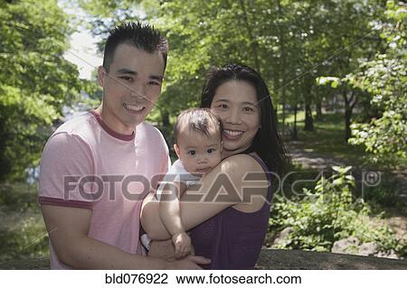 Stock Image - Chinese couple and baby in park. Fotosearch