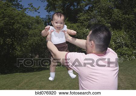 Chinese father lifting baby in park View Large Photo Image Stock Image - Chinese father lifting baby in park. Fotosearch