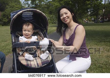 Stock Photo - Chinese mother and baby in stroller at park. Fotosearch
