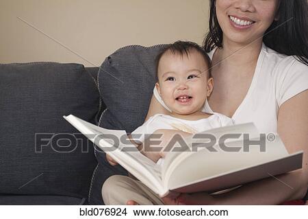 Chinese mother and baby reading book on sofa View Large Photo Image Picture - Chinese mother and baby reading book on sofa. Fotosearch