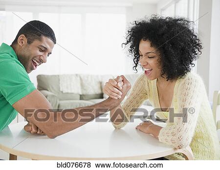 Stock Photo - Couple arm wrestling at table. Fotosearch