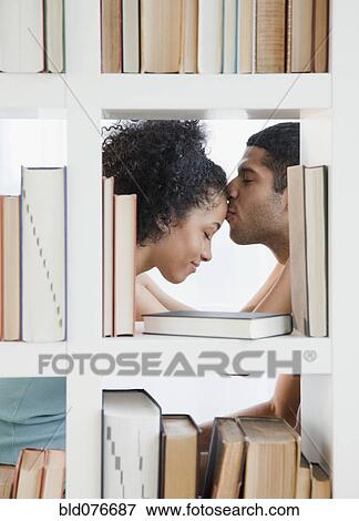 Couple kissing by bookcase View Large Photo Image Stock Photo - Couple kissing by bookcase. Fotosearch