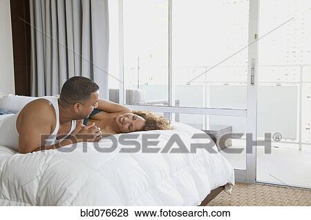 Couple laying on bed View Large Photo Image Stock Photo - Couple laying on bed. Fotosearch
