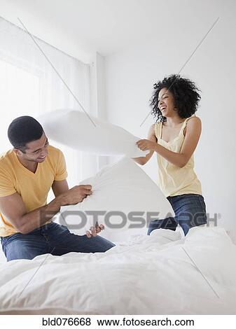 Stock Photo - Couple pillow fighting on bed. Fotosearch