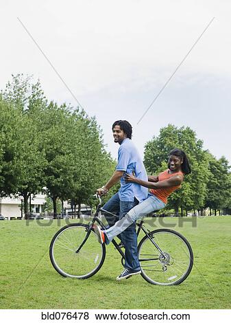 Stock Photo - Couple riding bicycle in park. Fotosearch