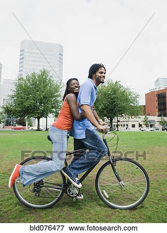 Stock Photo - Couple riding bicycle in urban park. Fotosearch