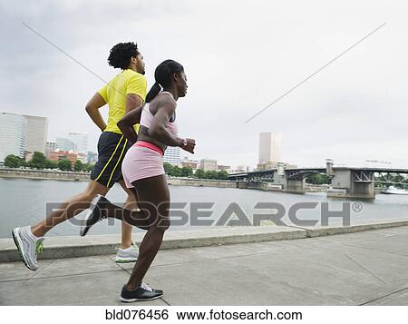 Couple running along urban waterfront View Large Photo Image Stock Photograph - Couple running along urban waterfront. Fotosearch