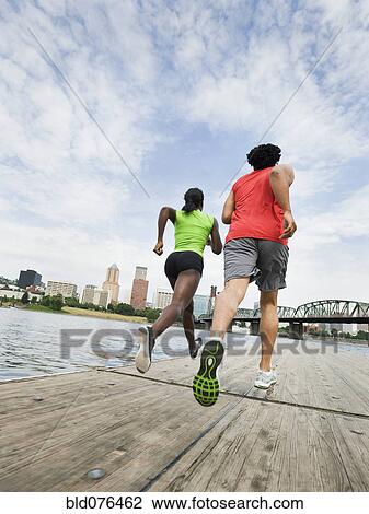 Couple running on urban boardwalk along river View Large Photo Image Stock Image - Couple running on urban boardwalk along river. Fotosearch