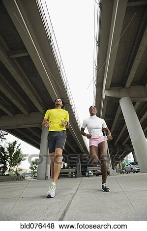 Stock Photo - Couple running under freeway overpass. Fotosearch