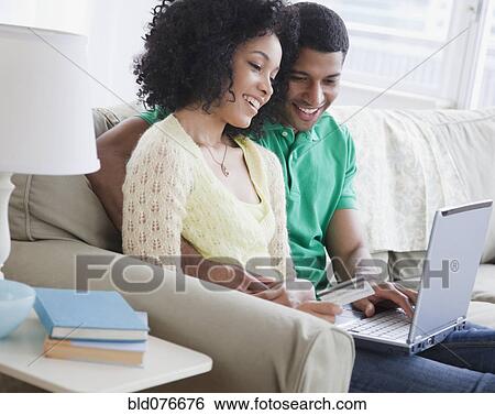 Couple shopping online in living room View Large Photo Image Stock Photograph - Couple shopping online in living room. Fotosearch