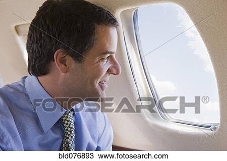 Hispanic businessman looking out airplane window View Large Photo Image Stock Image - Hispanic businessman looking out airplane window. Fotosearch