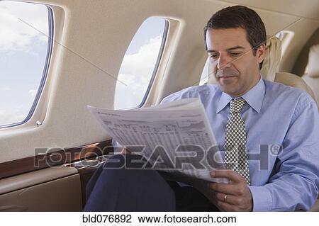 Hispanic businessman reading newspaper on airplane View Large Photo Image Stock Image - Hispanic businessman reading newspaper on airplane. Fotosearch