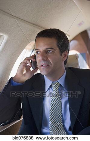 Hispanic businessman using cell phone on airplane View Large Photo Image Stock Photo - Hispanic businessman using cell phone on airplane. Fotosearch