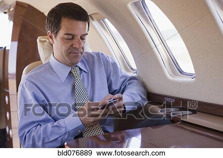 Hispanic businessman using cell phone on airplane View Large Photo Image Stock Photo - Hispanic businessman using cell phone on airplane. Fotosearch